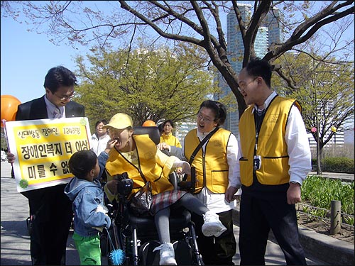 중증장애인 최윤희씨에게 사탕을 먹여주고 있는 동네 꼬마 